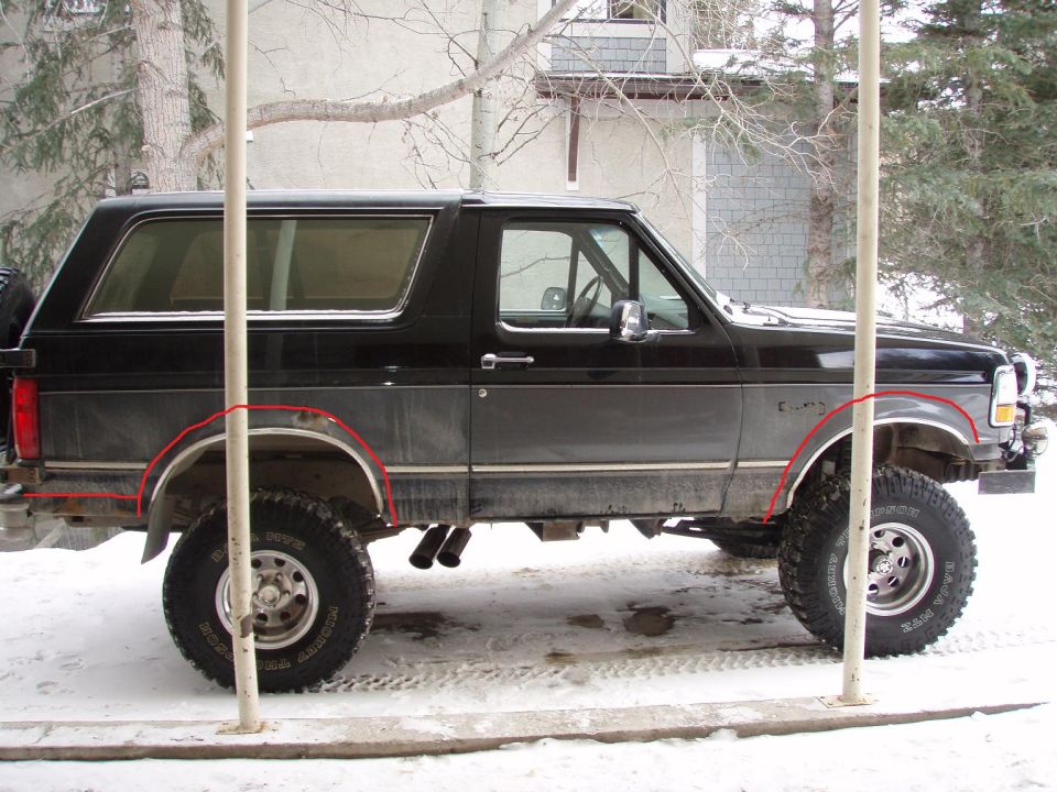 Lifted black Ford Bronco side view in snow with red fender-trim lines drawn on