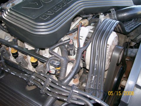 1995 Mercury Grand Marquis - Close-up view of the engine bay of a 1995 Mercury Grand Marquis, showing the fuel injectors, spark plug wires, and alternator.