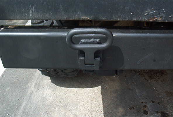 Rear receiver hitch and pintle-style tow loop under a dark truck on pavement