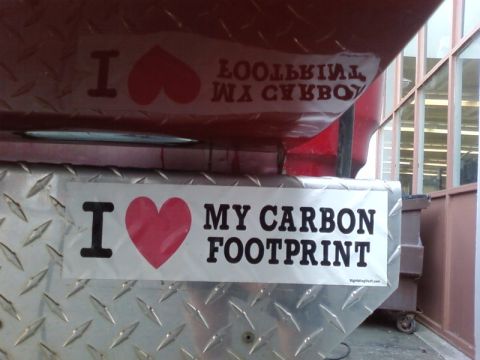 1995 Ford Bronco - A white bumper sticker with black text reads "I ❤️ MY CARBON FOOTPRINT" and is affixed to the red metal body of a vehicle. A second, identi…