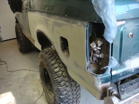 1996 Ford Bronco - Photograph of a Ford Bronco's rear quarter panel masked and sanded in primer during a body restoration, not a technical document.