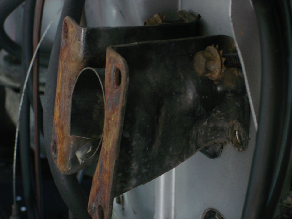Close-up of two rusty metal brackets on a vehicle frame.