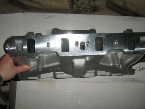 1988 Mercury Grand Marquis - A person's hand is holding up a polished aluminum intake manifold, showing the ports and bolt holes. The manifold is resting on a white box.