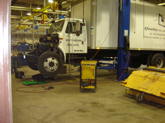 Photo of a box truck on a two-post lift inside a repair shop