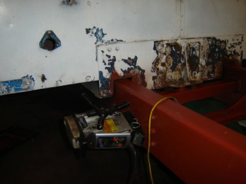 1992 Ford Bronco - Photograph of a truck body panel and red frame rail during disassembly, not a technical document.