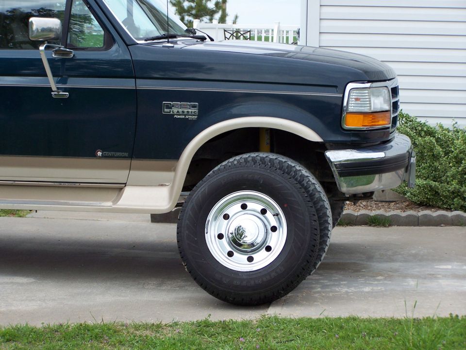 Dark blue and tan pickup truck, driver's side front quarter panel, fender, door, and wheel.