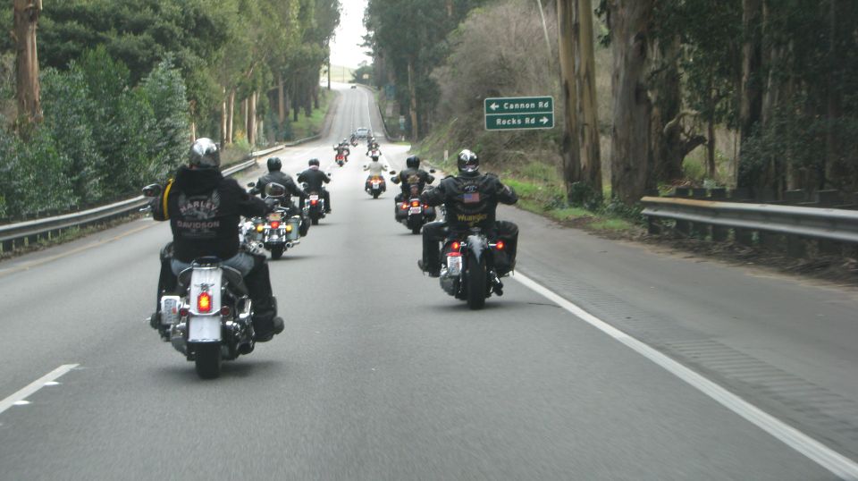 Motorcyclists riding on a road with trees and a road sign.