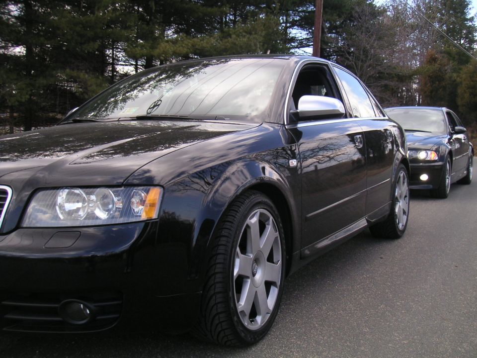 Black Audi sedan parked on the side of a road, front 3/4 view.