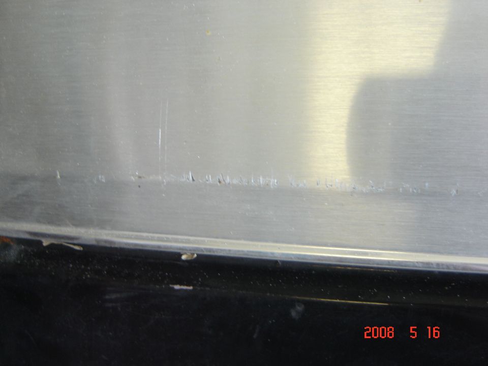 Brushed metal surface with scratches and a date stamp.