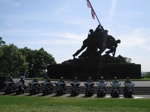 1991 Ford LTD Crown Victoria - line of police motorcycles is parked in front of the Iwo Jima Marine Corps War Memorial under a clear sky.