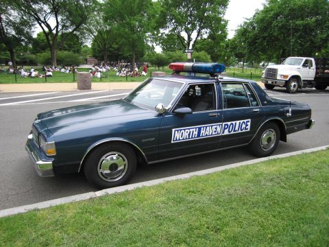1991 Ford LTD Crown Victoria - dark blue Chevrolet Caprice sedan lettered NORTH HAVEN POLICE with roof lights parked beside a grassy field.