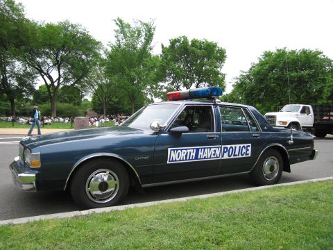 1991 Ford LTD Crown Victoria - Front three-quarter view of a dark blue Chevrolet Caprice NORTH HAVEN POLICE cruiser with a white truck behind it.