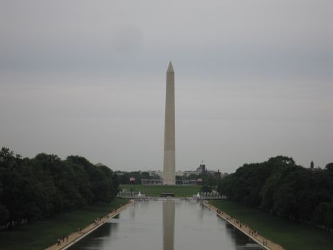 1991 Ford LTD Crown Victoria - Washington Monument rises beyond the reflecting pool, framed by trees on a hazy overcast day.