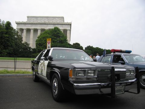 1991 Ford LTD Crown Victoria - black-and-white Ford police sedan with roof lightbar parked before the columned Lincoln Memorial.