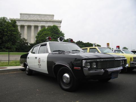 1991 Ford LTD Crown Victoria - black-and-white AMC Matador police sedan with twin roof speakers parked before the Lincoln Memorial.