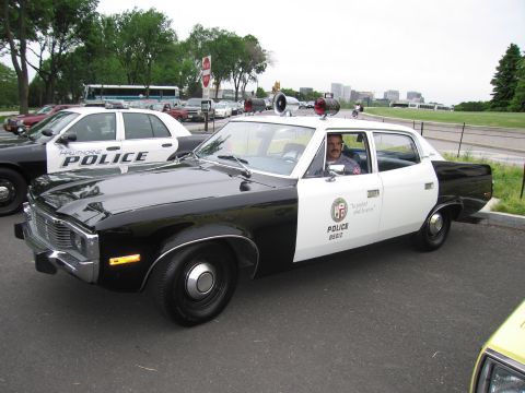 1991 Ford LTD Crown Victoria - black-and-white AMC Matador LAPD police car marked POLICE 85012 with roof loudspeaker, driver seated inside, near a highway.