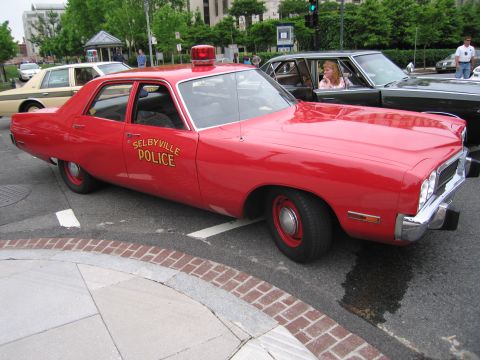 1991 Ford LTD Crown Victoria - red early-1970s four-door police sedan lettered SELBYVILLE POLICE with a single roof beacon is parked at a brick-lined curb.