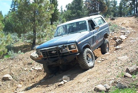 1986 Ford Bronco - 1986 Ford Bronco navigating a challenging off-road path.