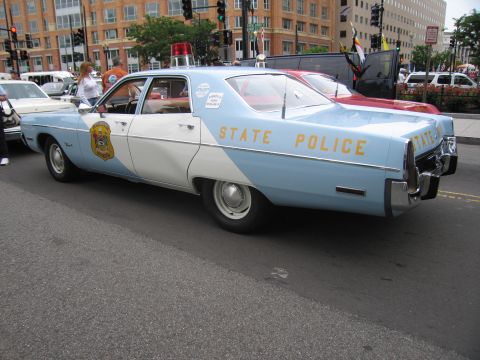 1991 Ford LTD Crown Victoria - light blue and white four-door STATE POLICE sedan with a gold door emblem and roof beacon is parked on a downtown street.