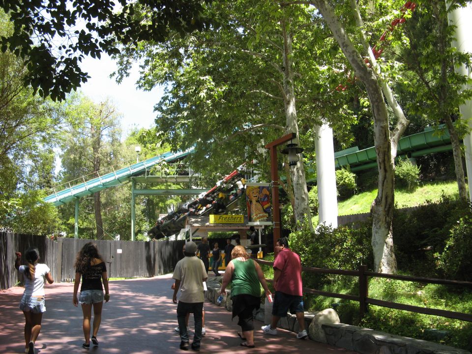 Amusement park roller coaster with people walking on a path.