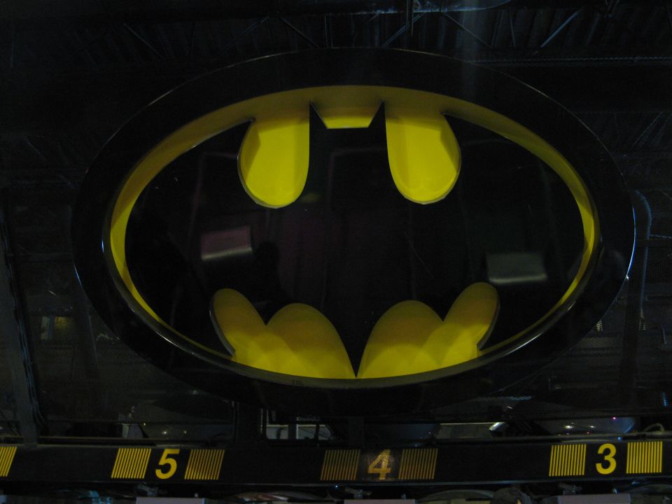 Close-up of a Batman logo with yellow accents and numbers 5, 4, 3 below.
