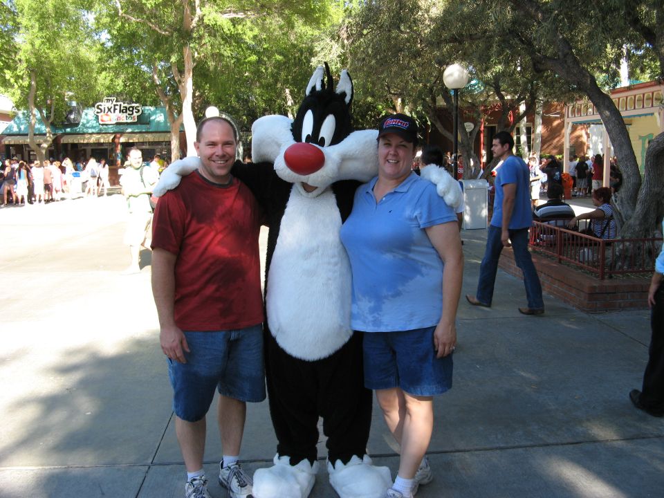 A man and a woman pose with Sylvester the Cat at Six Flags.