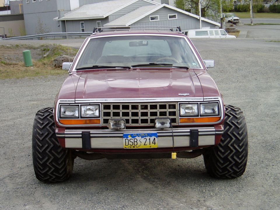 Maroon AMC Eagle SUV with large off-road tires and Alaska license plate.