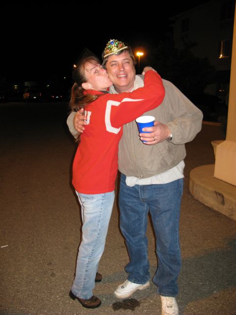 1985 Ford LTD Crown Victoria - A woman kisses a man who is wearing a crown and holding a blue cup.