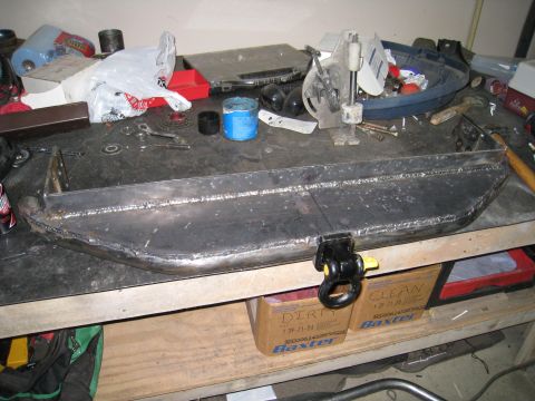 1996 Ford Bronco - A custom-welded bumper with a tow hitch is displayed on a workbench, surrounded by tools and supplies.