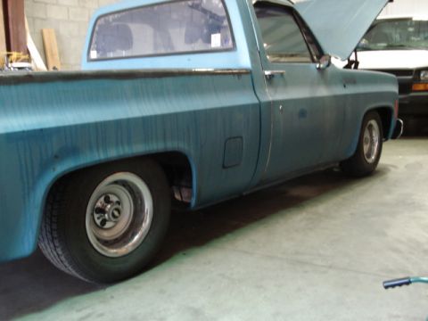 1979 Chevrolet C/K Pickup - A blue 1979 Chevrolet C/K Pickup is shown in a garage with its hood open, and another vehicle is visible in the background.