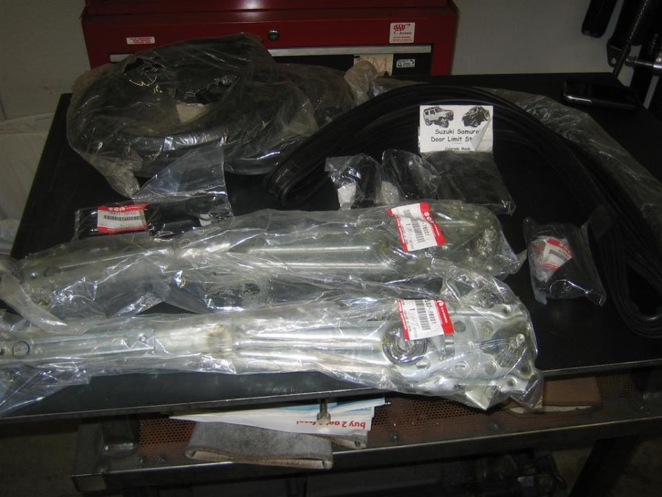 New Suzuki door window regulators, weatherstrip and limit strap kit on a workbench