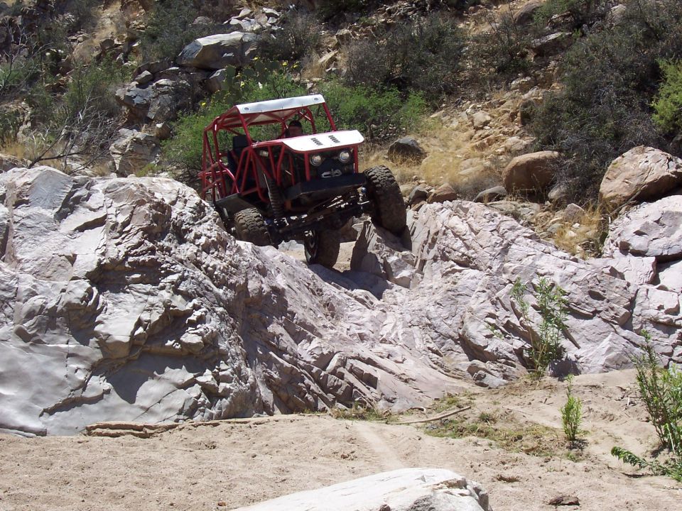 Red off-road buggy navigating rocky terrain
