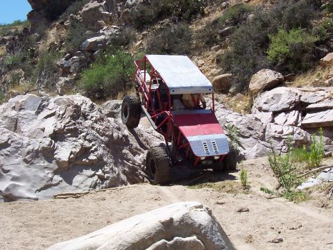 1981 Ford F-150 - This custom buggy navigates a challenging, rocky terrain with its occupants inside.