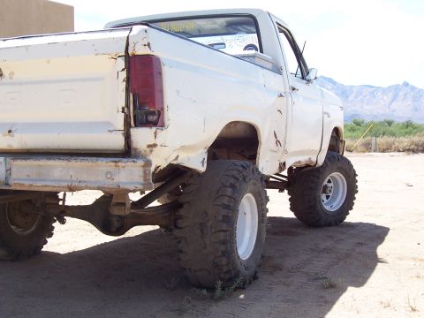 1981 Ford F-150 - A heavily modified white Ford pickup truck with a lifted suspension and off-road tires is parked outdoors.