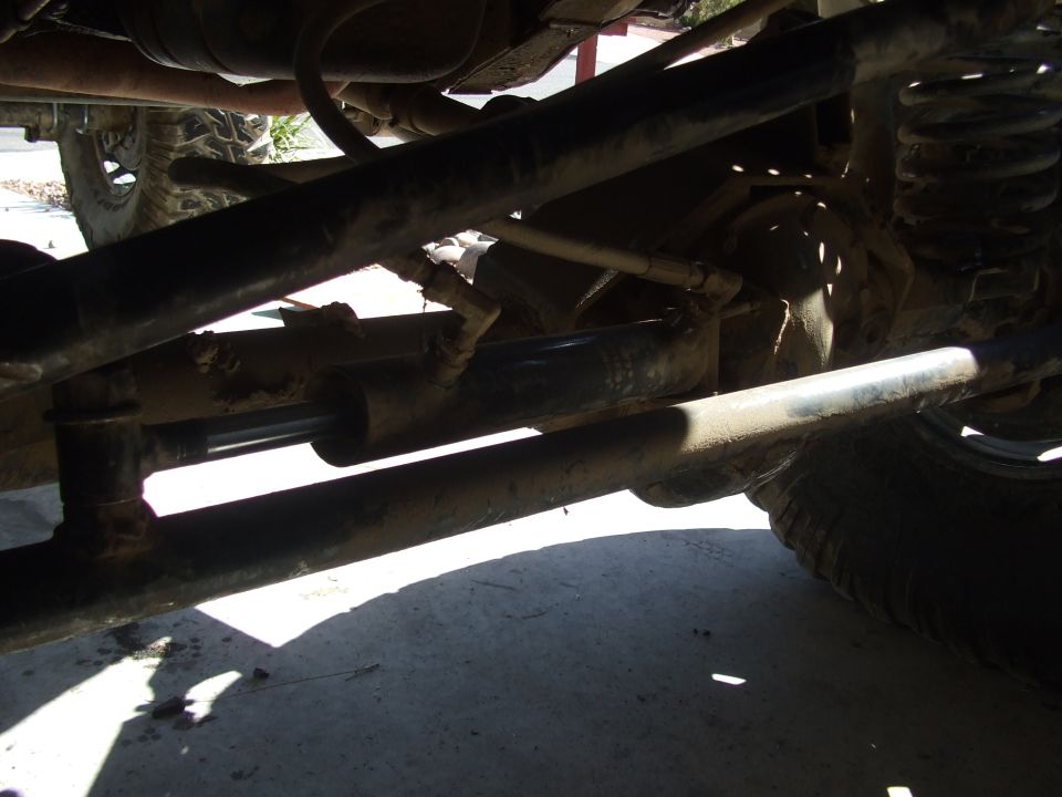 Undercarriage of a vehicle with visible suspension components, steering linkage, and a tire