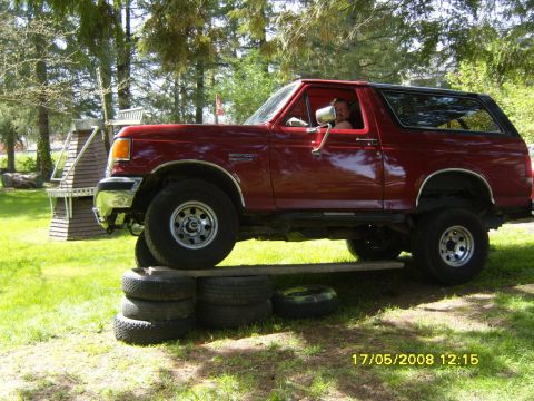 1989 Ford Bronco - A red 1989 Ford Bronco is positioned on stacked tires, demonstrating its articulation.