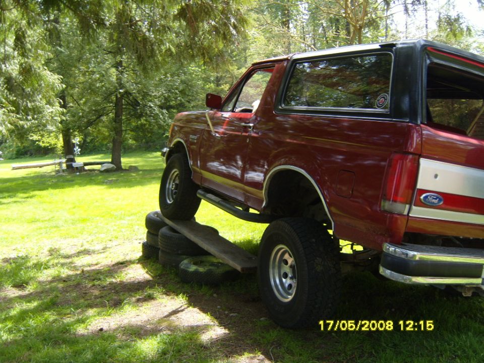 1989 Ford Bronco with its front wheels on a ramp and rear wheels on stacked tires