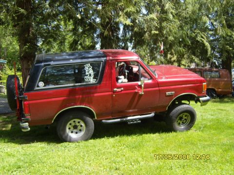 1989 Ford Bronco - This red 1989 Ford Bronco features a black removable top and a spare tire mounted on the tailgate.