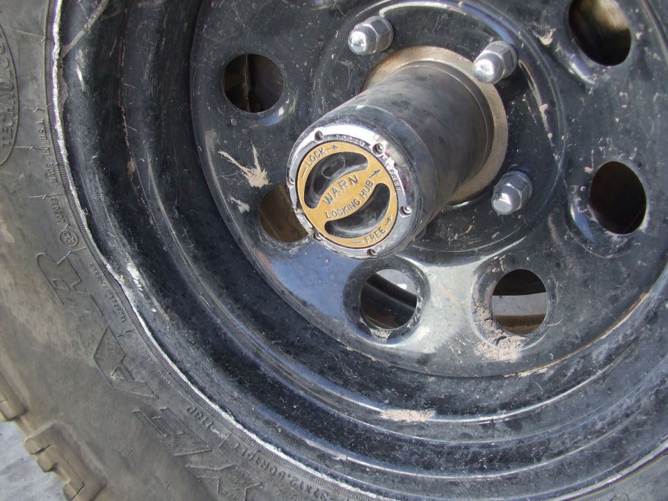 Close-up of a Warn locking hub on a vehicle wheel, set to 'LOCK'