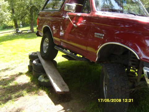 1989 Ford Bronco - 1989 Ford Bronco positioned on stacked tires with a wooden ramp for articulation testing.