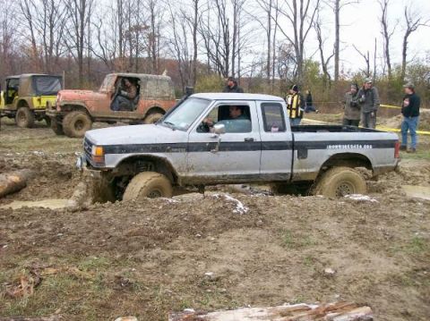 1990 Ford Ranger - Off-road vehicles navigate a muddy course, with a Ford Ranger prominently stuck.