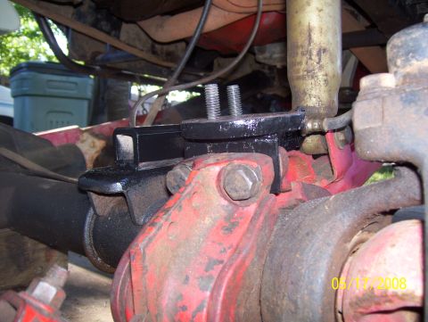 1978 Ford Bronco - Close-up of a vehicle's suspension part, showing a black bracket attached to a red differential.