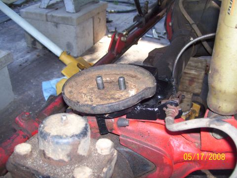 1978 Ford Bronco - Close-up of a vehicle suspension part, likely a coil mount, with visible bolts and red components.