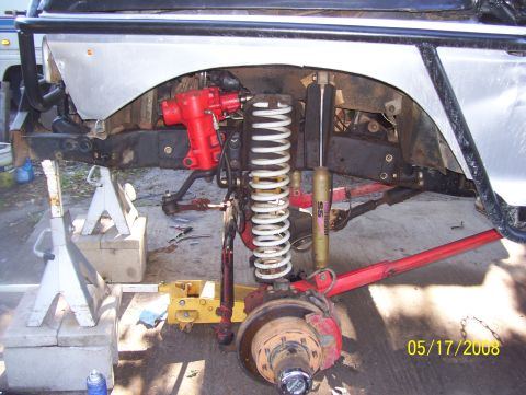 1978 Ford Bronco - Close-up view of the front suspension and steering components, including a red steering box and white coil springs, on a vehicle undergoing…