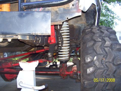 1978 Ford Bronco - Close-up view of the front suspension and large off-road tire on a 1978 Ford Bronco, supported by a jack stand.