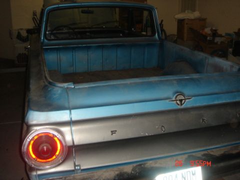 1965 Ford Ranchero - The rear of a blue 1965 Ford Ranchero pickup truck is visible, with its tailgate and taillight clearly depicted.