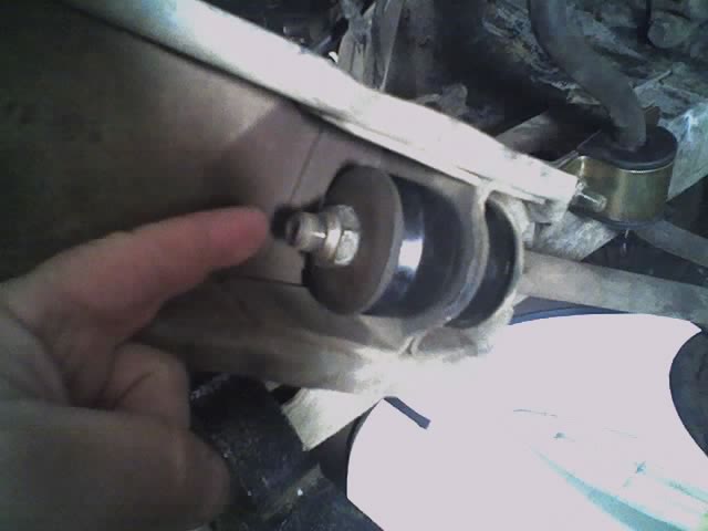 Close-up of a suspension component with a finger pointing to a bolt