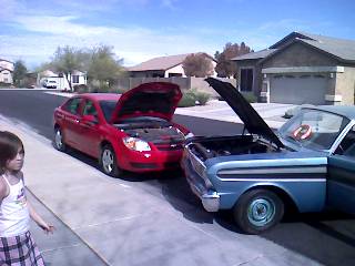1965 Ford Ranchero - A blue 1965 Ford Ranchero is parked on the street with its hood open, next to a red sedan.