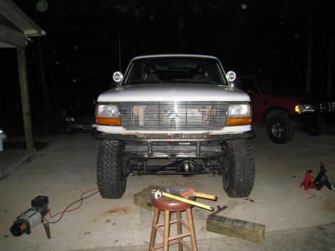 1996 Ford Bronco - A white Ford Bronco is parked outside at night, a custom bumper and off-road modifications.