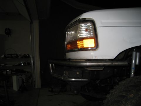 1996 Ford Bronco - Close-up of a white Ford truck's front end, showing an aftermarket bumper and turn signal light.